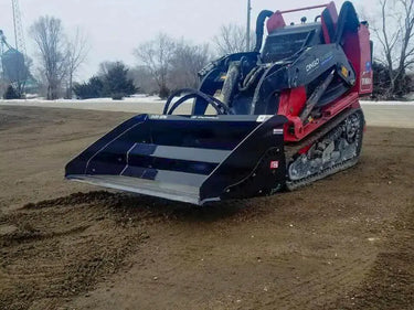 A Toro Dingo TCD skid steer loader with a mini hydra-bucket attachment sitting on a dirt field.